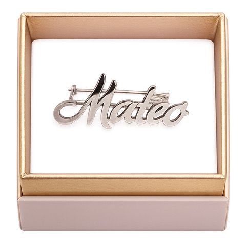 Alfiler plateado con el nombre «Mateo» en letra caligráfica, dentro de una caja dorada